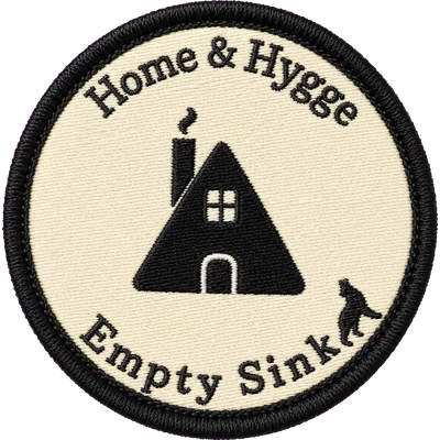Embroidered Home & Hygge patch — an A-frame cabin with a smoking chimney on cream